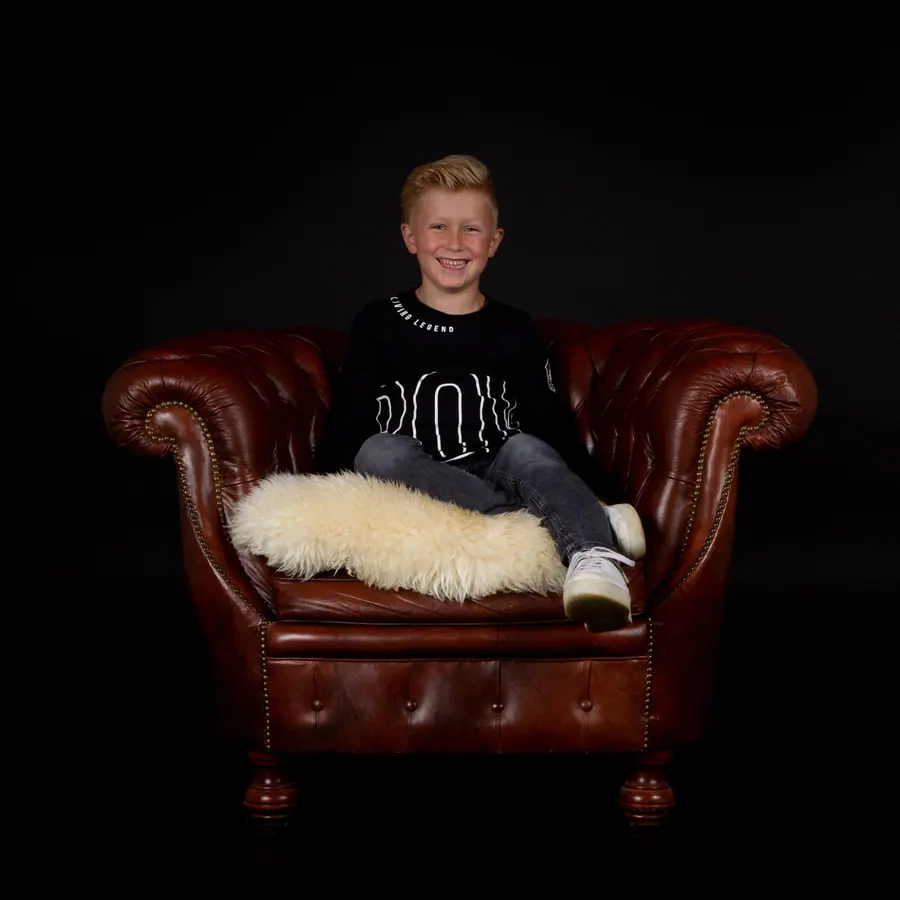 Jongen in een leren fauteuil met een schapenvacht